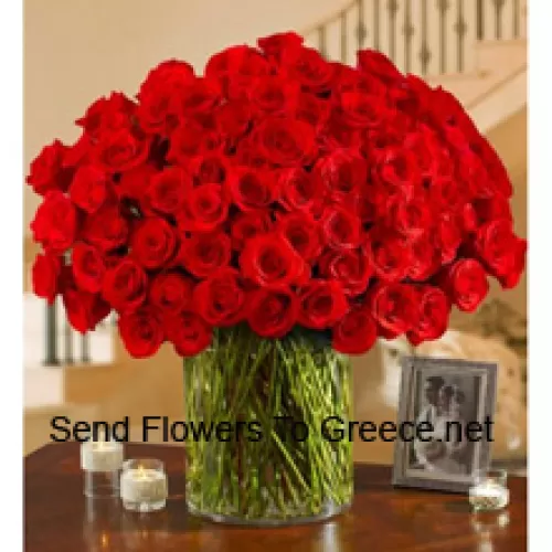 101 rode rozen met wat varens in een grote glazen vaas