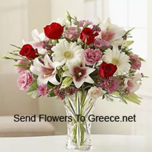 Punaiset ruusut, vaaleanpunaiset neilikat, valkoiset gerberat ja valkoiset liljat muiden sekalaisien kukkien kanssa lasimaljakossa