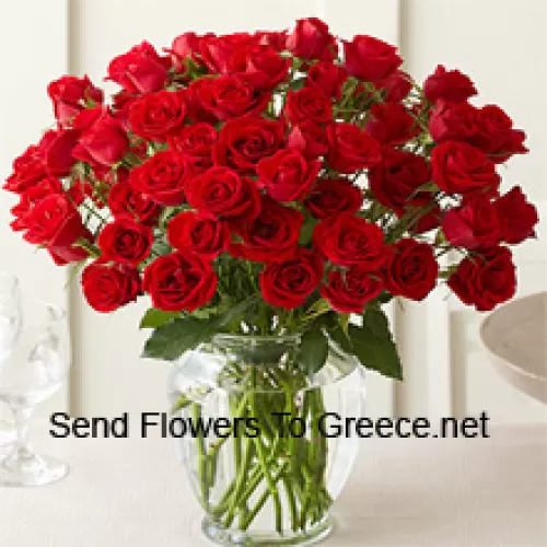 51 crvena ruža s nekim paprati u staklenoj vazi