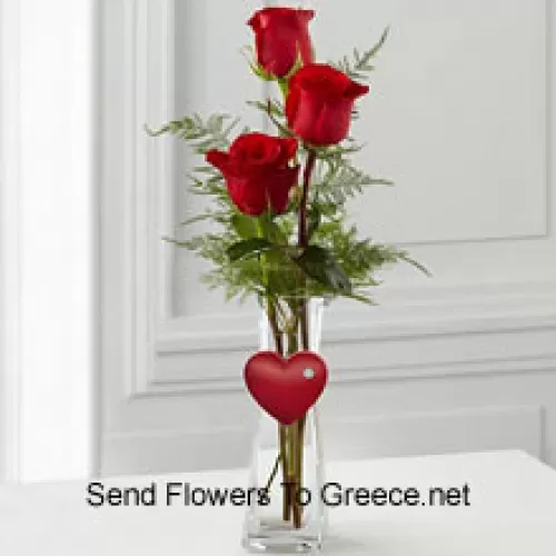 玻璃花瓶中的3朵红玫瑰，配有小心形装饰