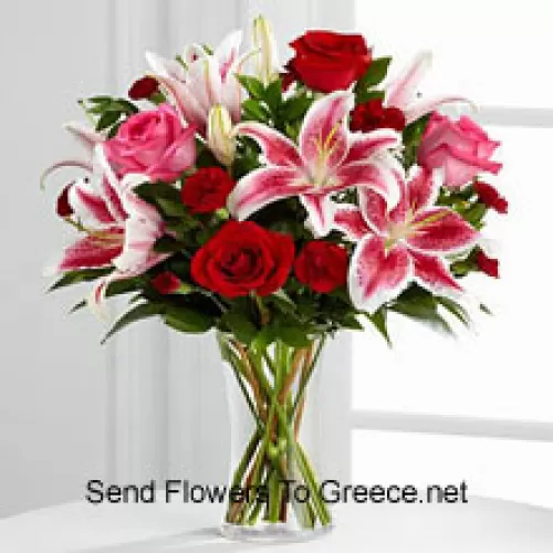유리 꽃병에 담긴 빨간색과 분홍색 장미와 분홍색 릴리와 계절적인 채움재료